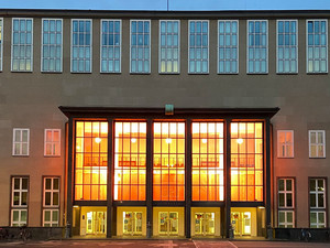 Orange angestrahltes Hauptgebäude der Uni Köln 