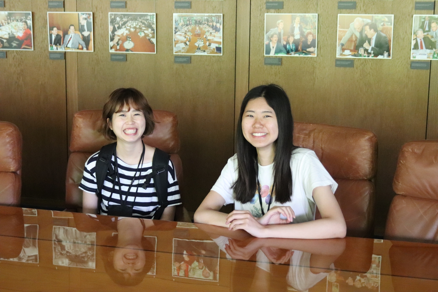 Two students sitting at a conference table in big leather chairs.