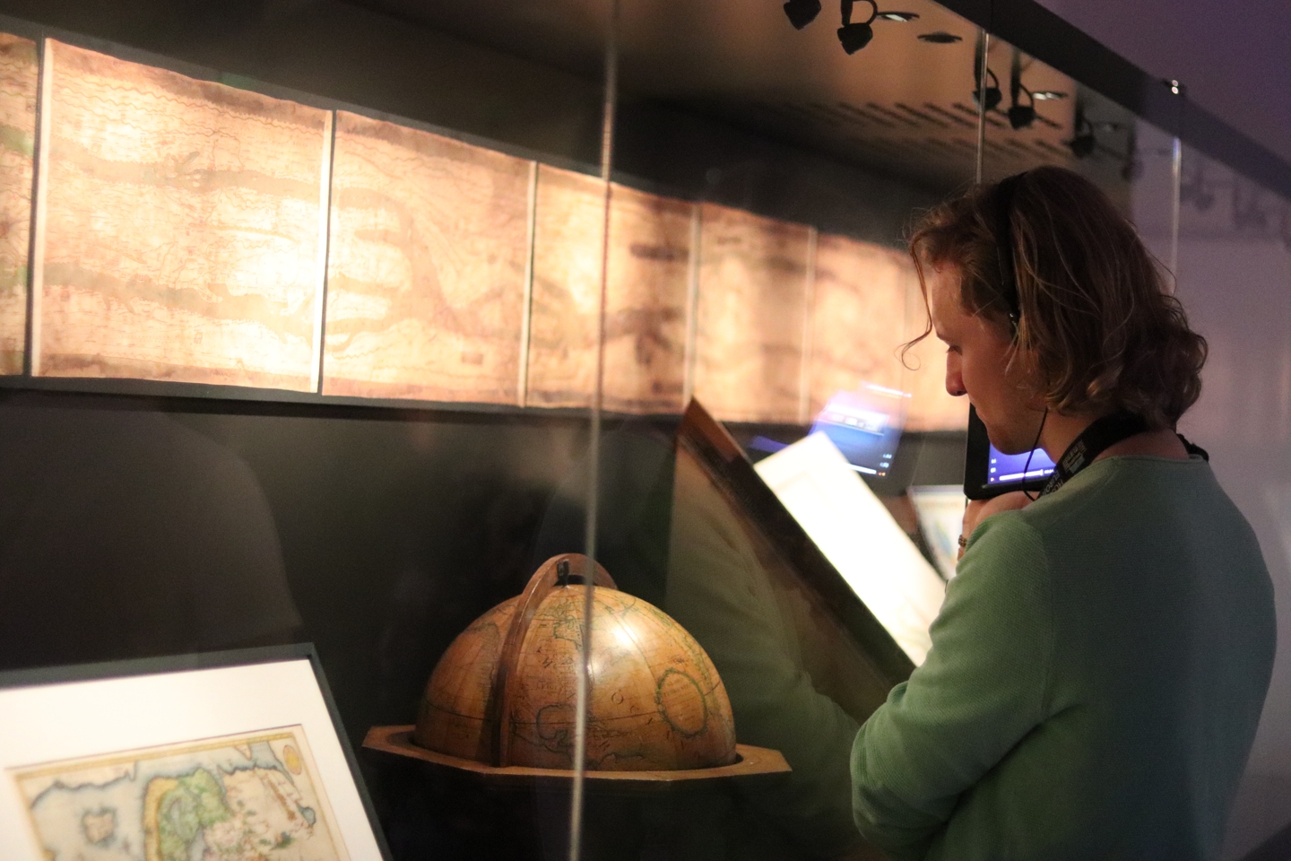 Student looking at the exhibits, an old map and globe, at the museum